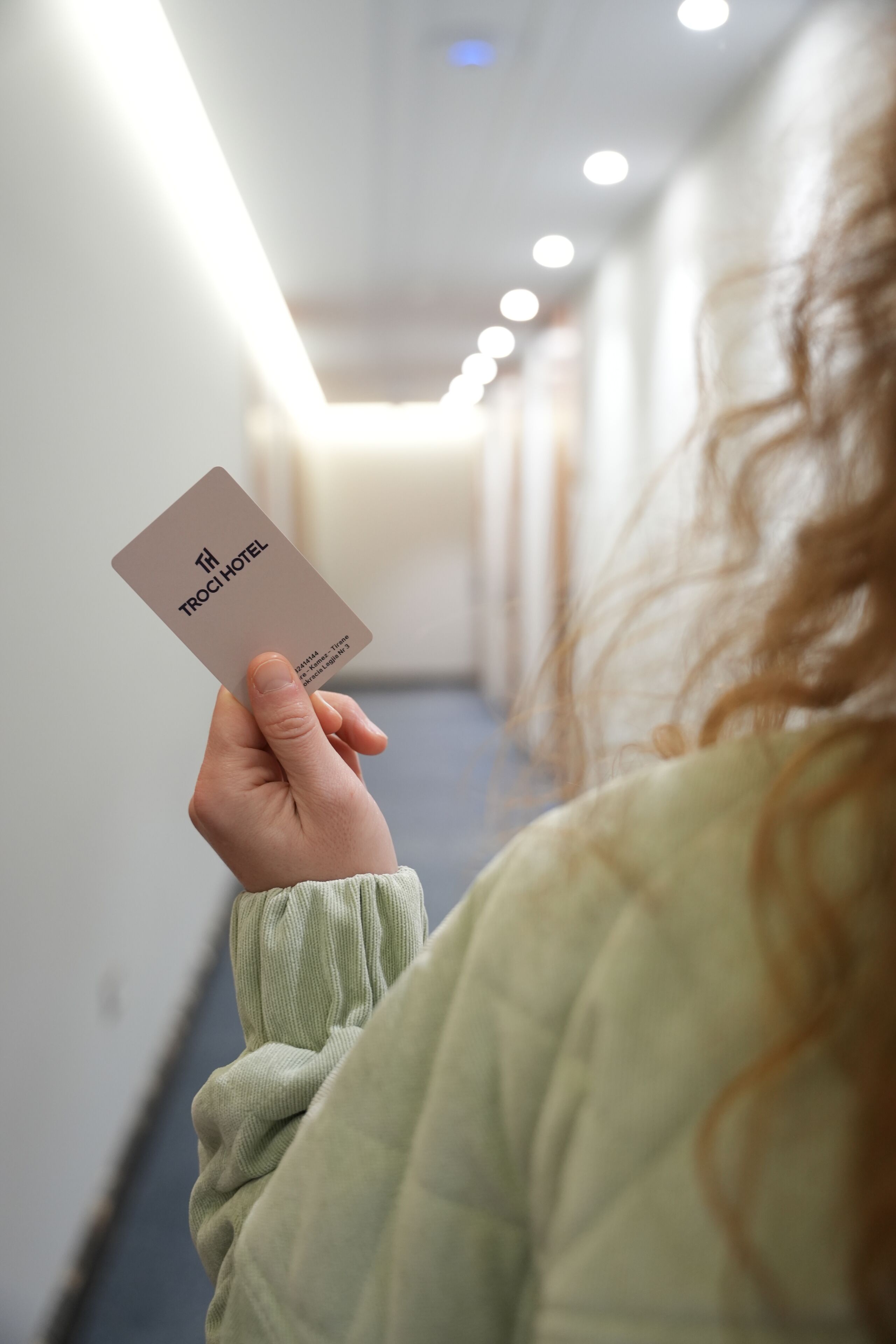 Henkilö, jolla on kädessään kortti, jossa lukee ”TRI HOTEL”.