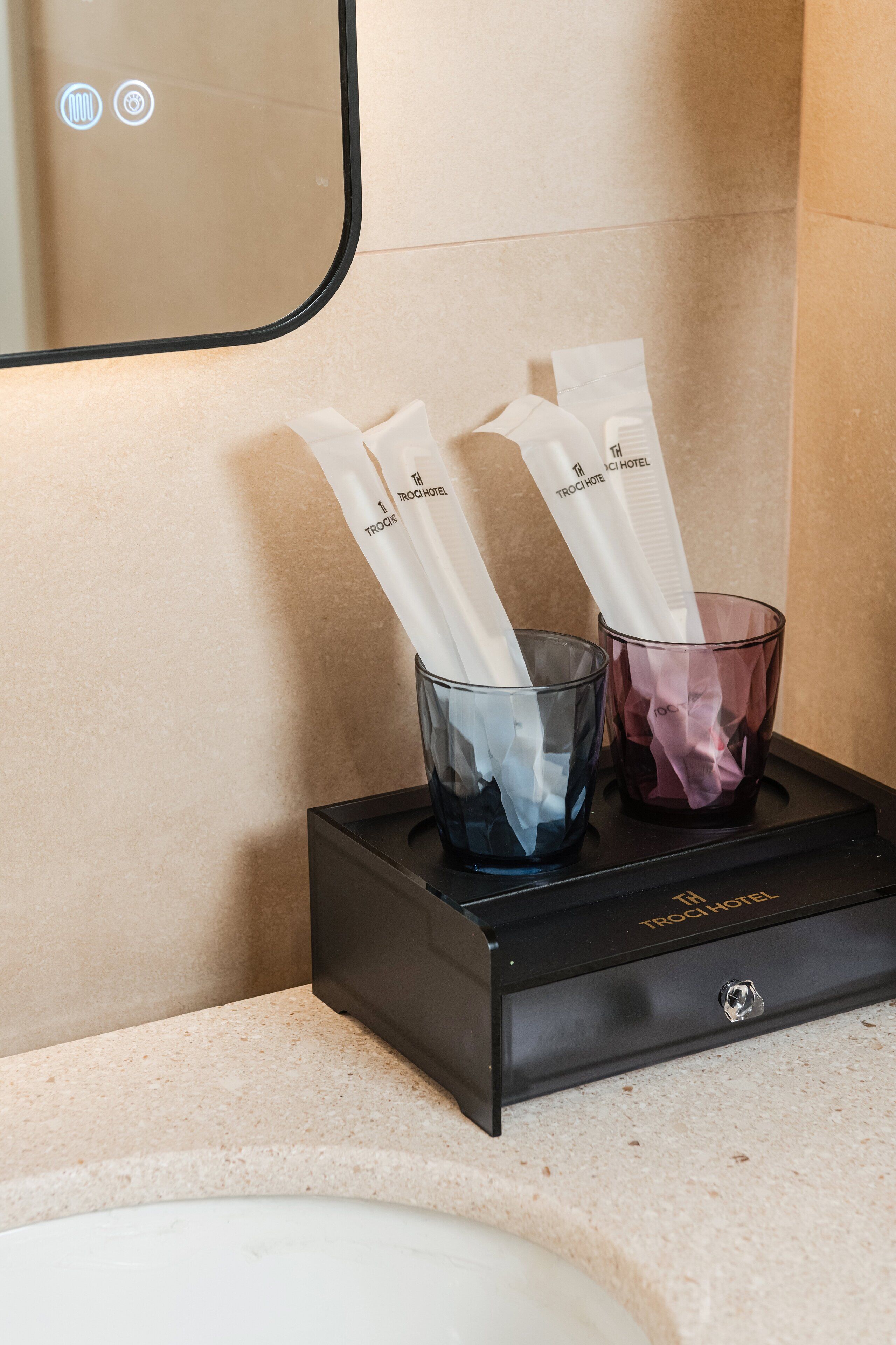 A black tray with two glasses containing white napkins and a name tag, placed on a countertop near a sink.