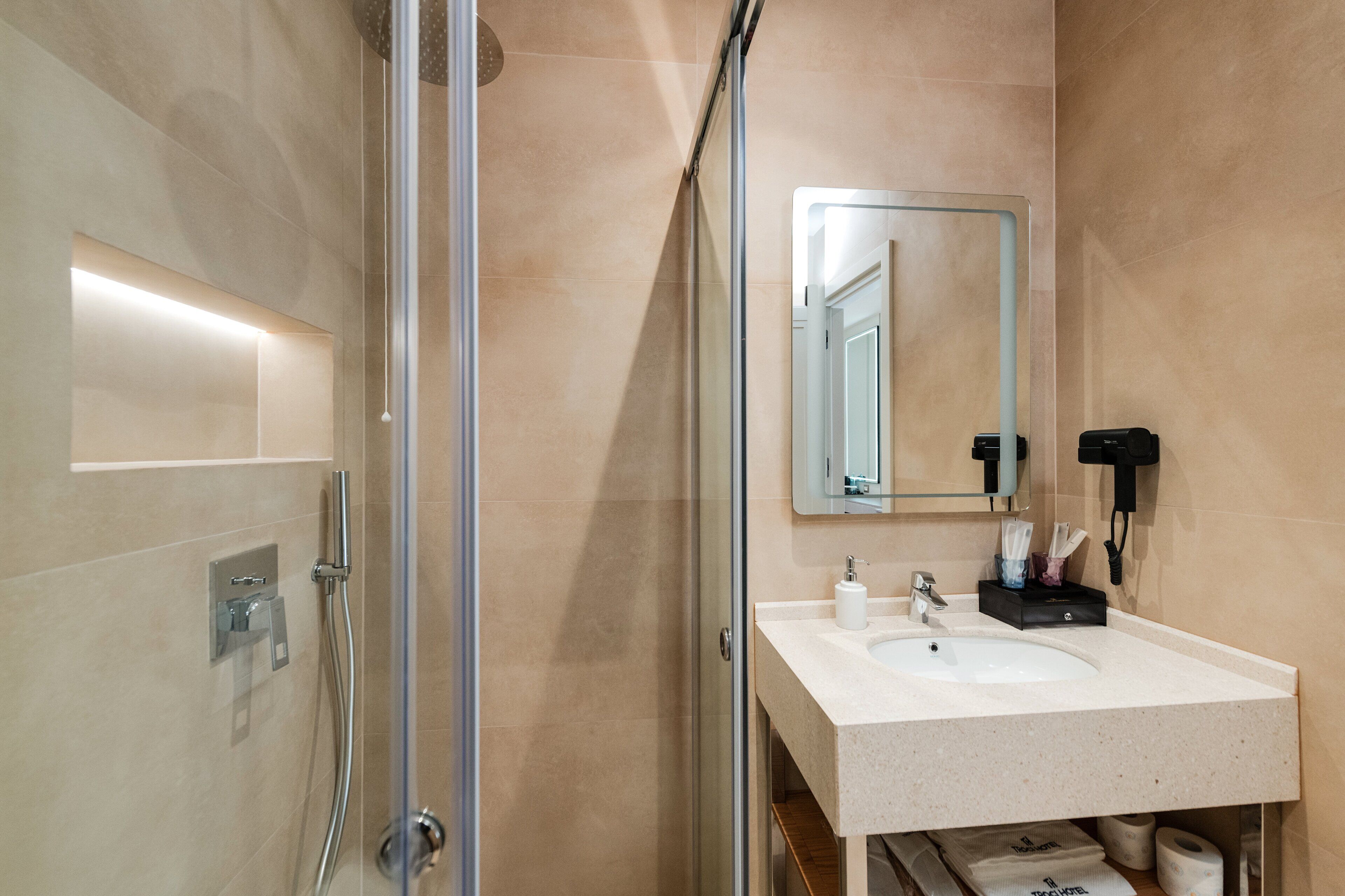 Un baño moderno con cabina de ducha de vidrio, un lavabo blanco y un espejo.