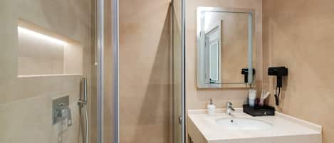 Un baño moderno con cabina de ducha de vidrio, un lavabo blanco y un espejo.
