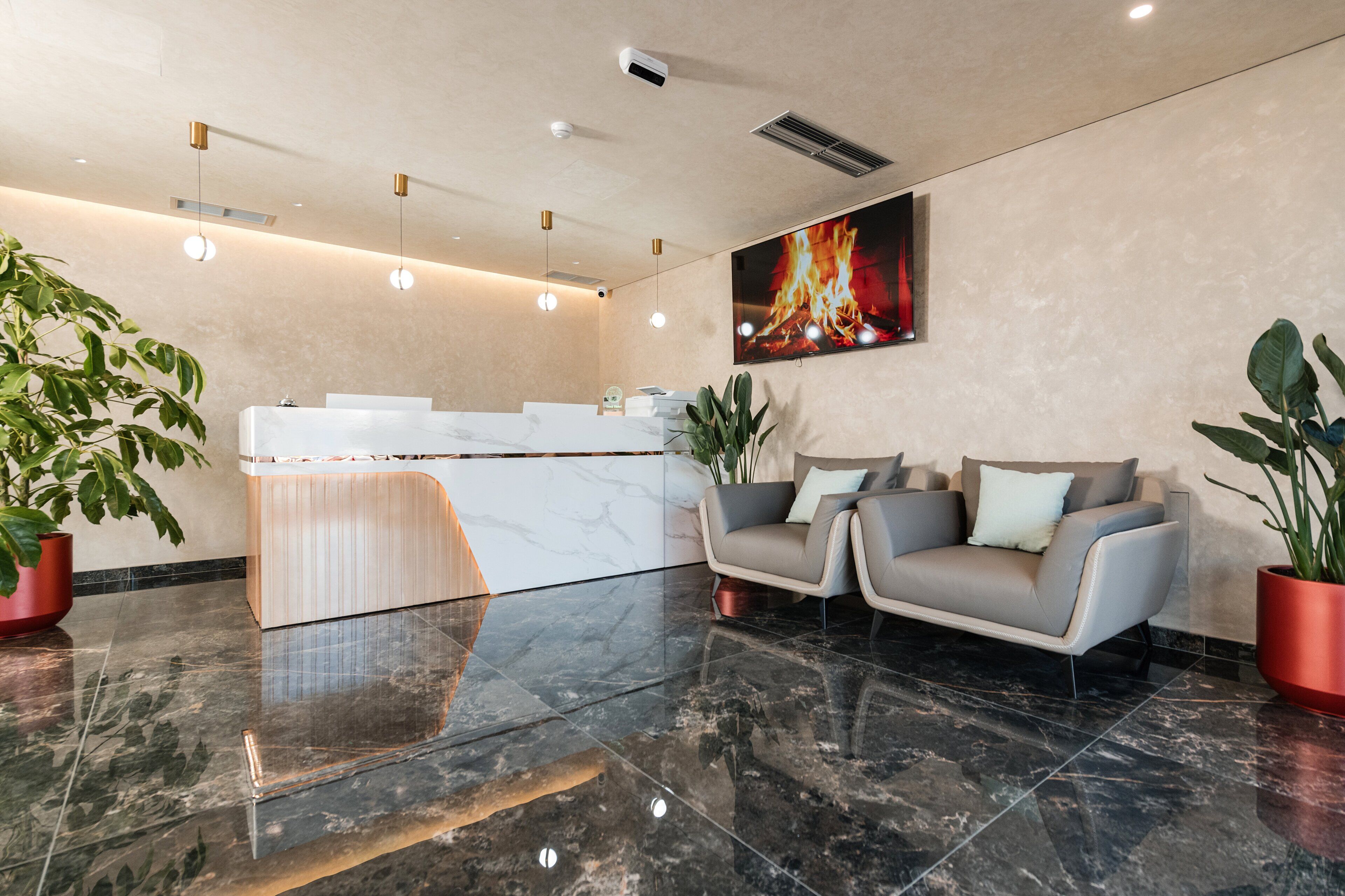 Ein moderner Empfangsbereich mit einer Marmor-Theke, zwei Sofas und Topfpflanzen.
