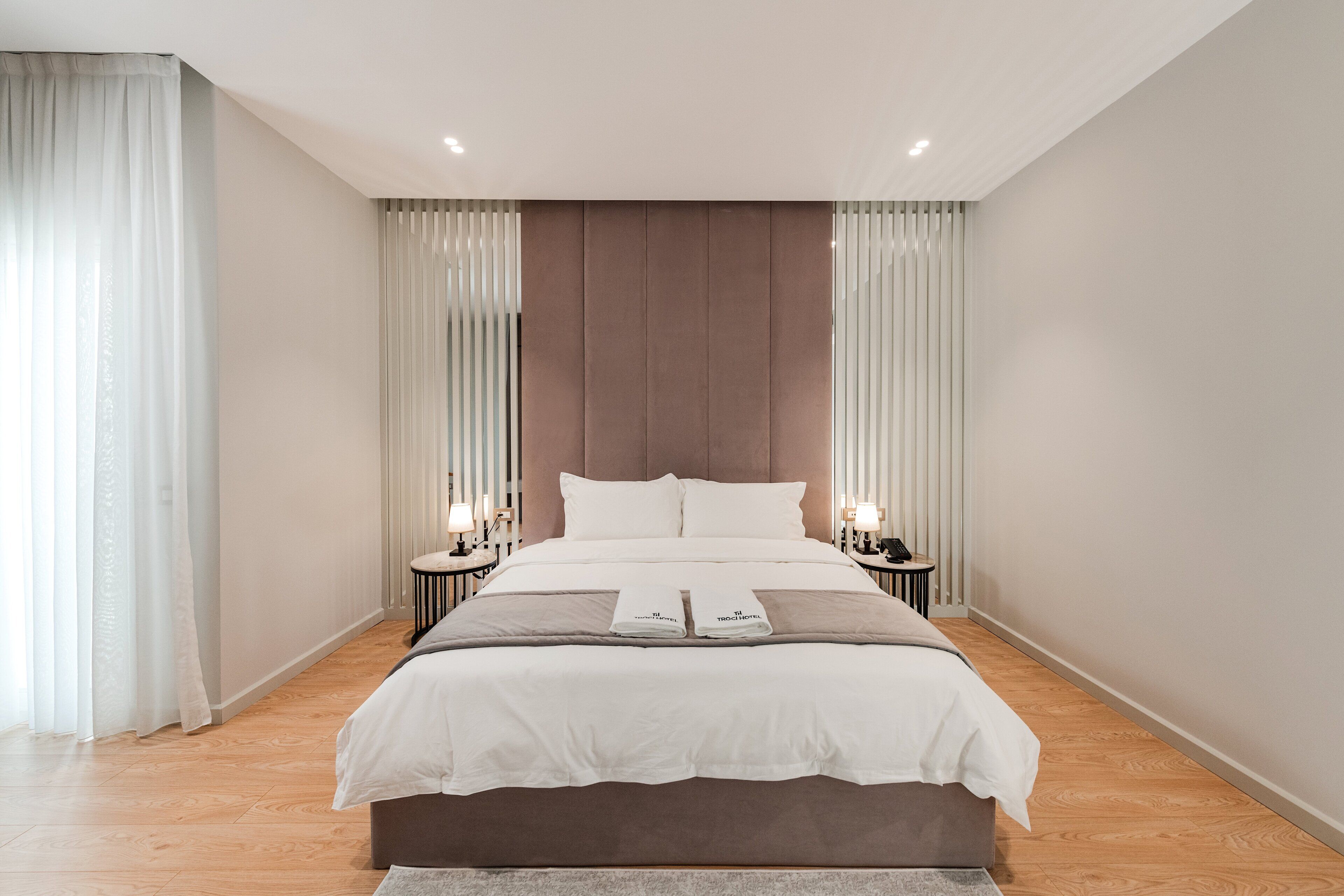 Una camera da letto moderna con un letto grande, due comodini con lampade e tende leggere.