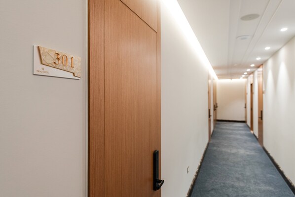 Un pasillo de hotel con puertas de madera, una alfombra azul y un letrero que indica la habitación 301.