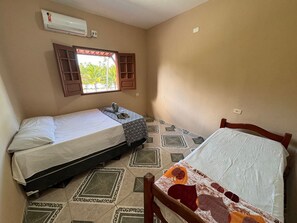 A small, compact room with two beds, a window with wooden shutters, and a tiled floor with a geometric pattern. - Xaréu Flats Maragogi (Maragogi)