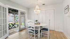 A dining area with a white table and chairs, a chandelier, and a door with a welcome sign.