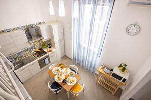 Cocina compacta con comedor, una pequeña mesa con desayuno y un reloj en la pared.