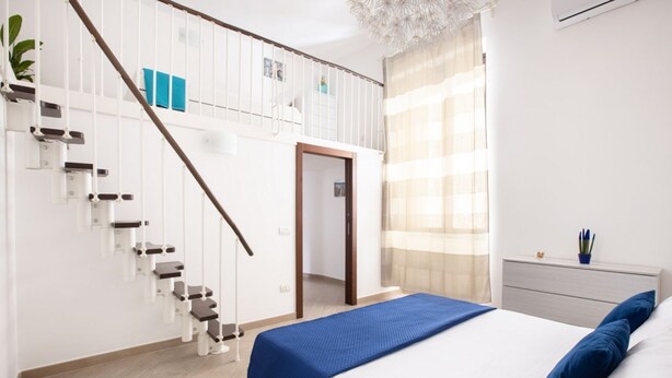 A modern bedroom with a large bed, a staircase, and a small balcony. - Cosy house under the Arches in Sorrento Old Town (Sorrento)