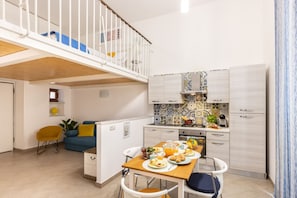 Un apartamento pequeño con zona de comedor, kitchenette y balcón.