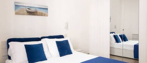 A hotel room with a bed, a nightstand, a mirror, and a painting on the wall.