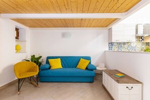 A room with a blue sofa, yellow cushions, a yellow chair, a white cabinet, and a wooden ceiling. - Cosy house under the Arches in Sorrento Old Town (Sorrento)