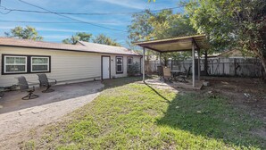 A residential backyard with a covered patio, a fenced yard, and a house with a garage.