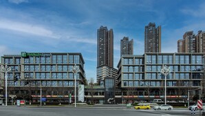 A modern hotel with multiple floors, large windows, and a Holiday Inn Express sign. - Holiday Inn Express Chongqing Nanbin Road by IHG (Chongqing)