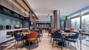 A modern restaurant with a long counter, blue and orange chairs, and large windows offering a view of the outside. - Holiday Inn Express Chongqing Nanbin Road by IHG (Chongqing)