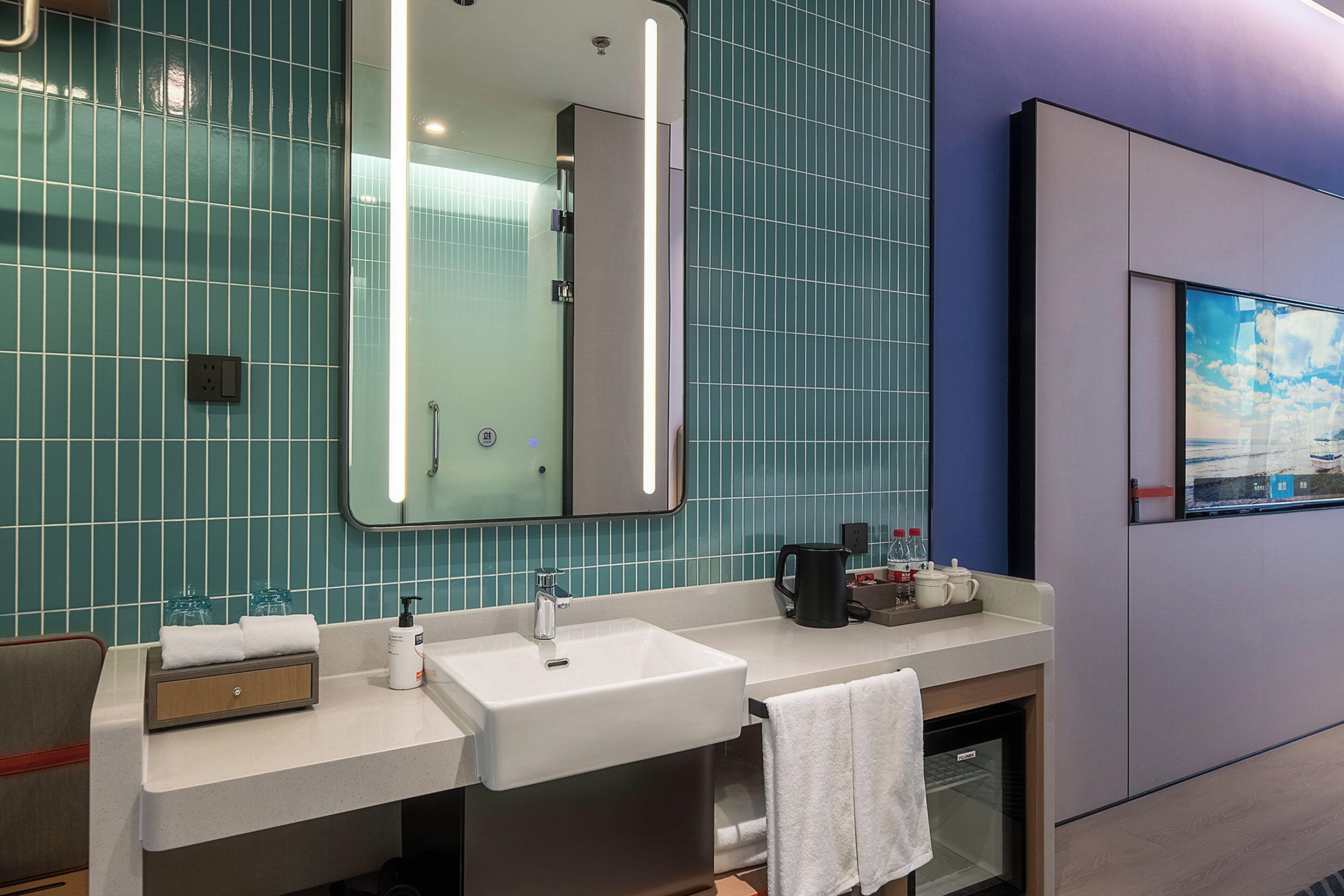 A modern bathroom with a dual sink vanity, a large mirror, and a wall-mounted television.
