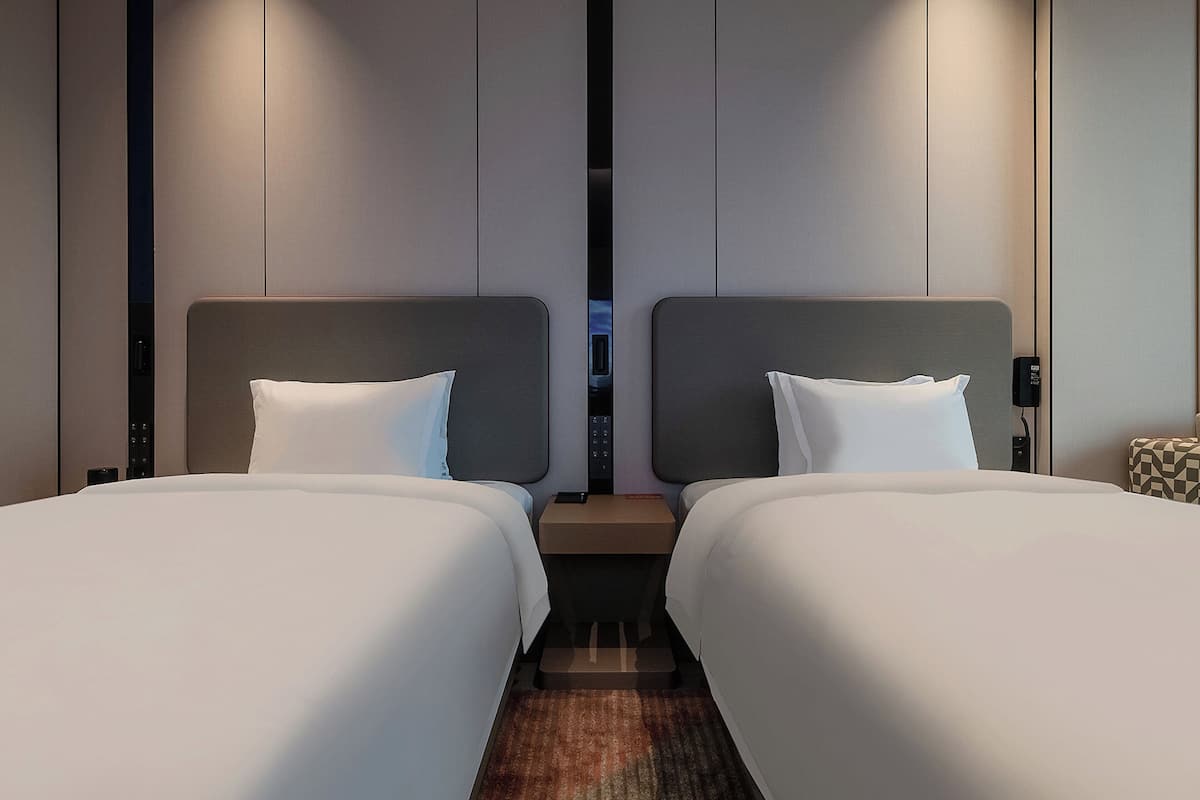 Ein Hotelzimmer mit zwei Betten, einem Nachttisch und einer Lampe.