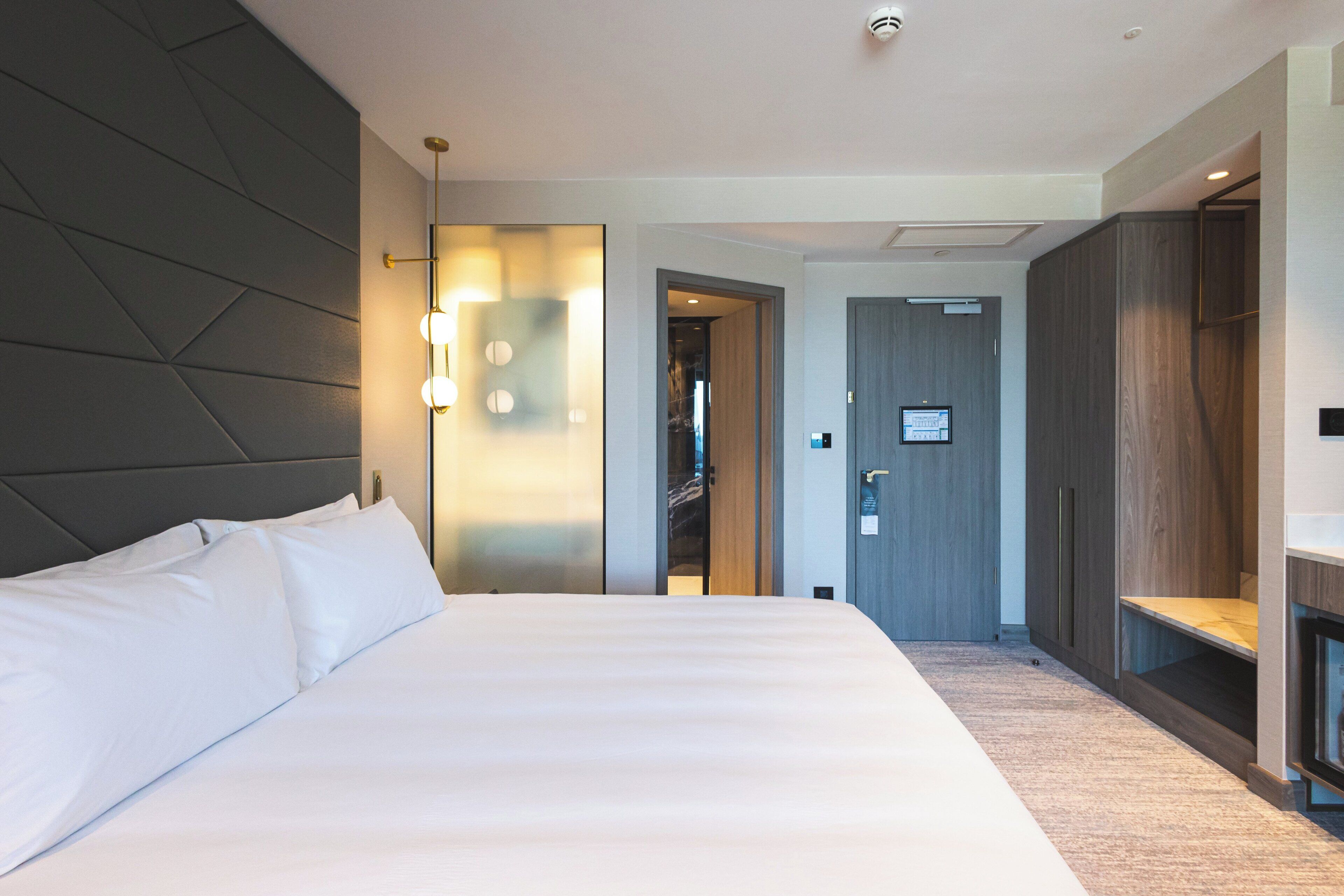 A modern hotel room with a large bed, a wardrobe, and a walk-in closet.