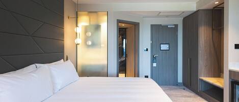 A modern hotel room with a large bed, a wardrobe, and a walk-in closet.