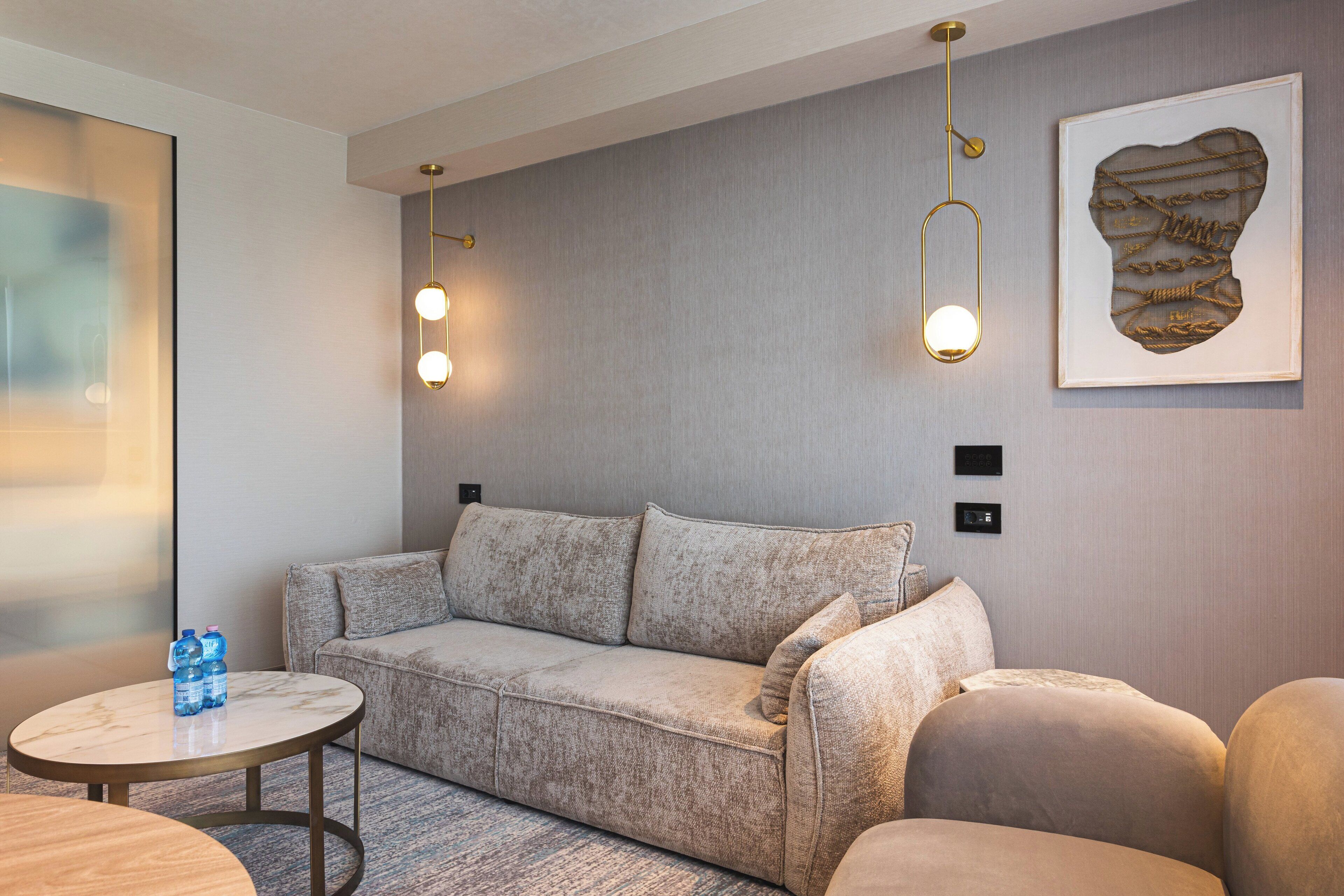 Ein modernes Wohnzimmer mit einem grauen Sofa, einem runden Couchtisch und zwei Pendelleuchten.