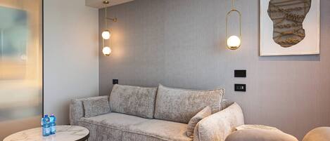 Een moderne woonkamer met een grijze bank, een ronde salontafel en twee hanglampen.