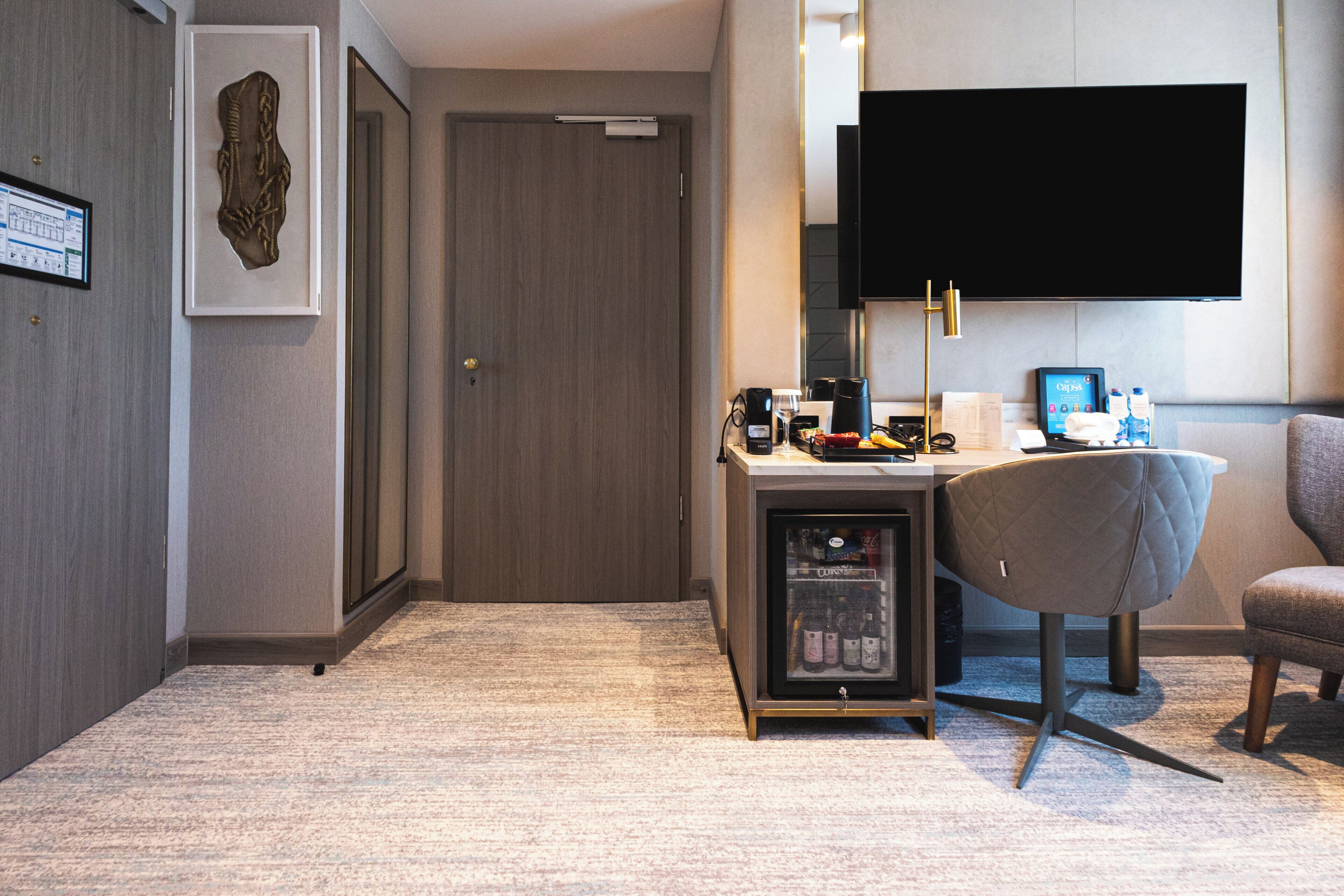 Une chambre d’hôtel équipée d’un bureau, d’une chaise, d’une télévision et d’un mini-bar.