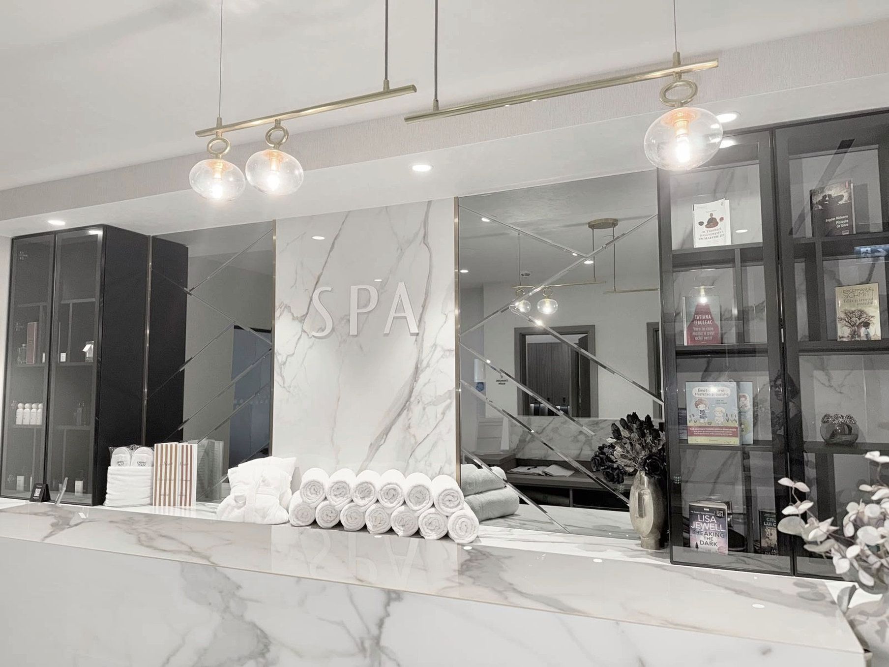 A spa with a marble reception desk, towels, and a glass display of spa products.