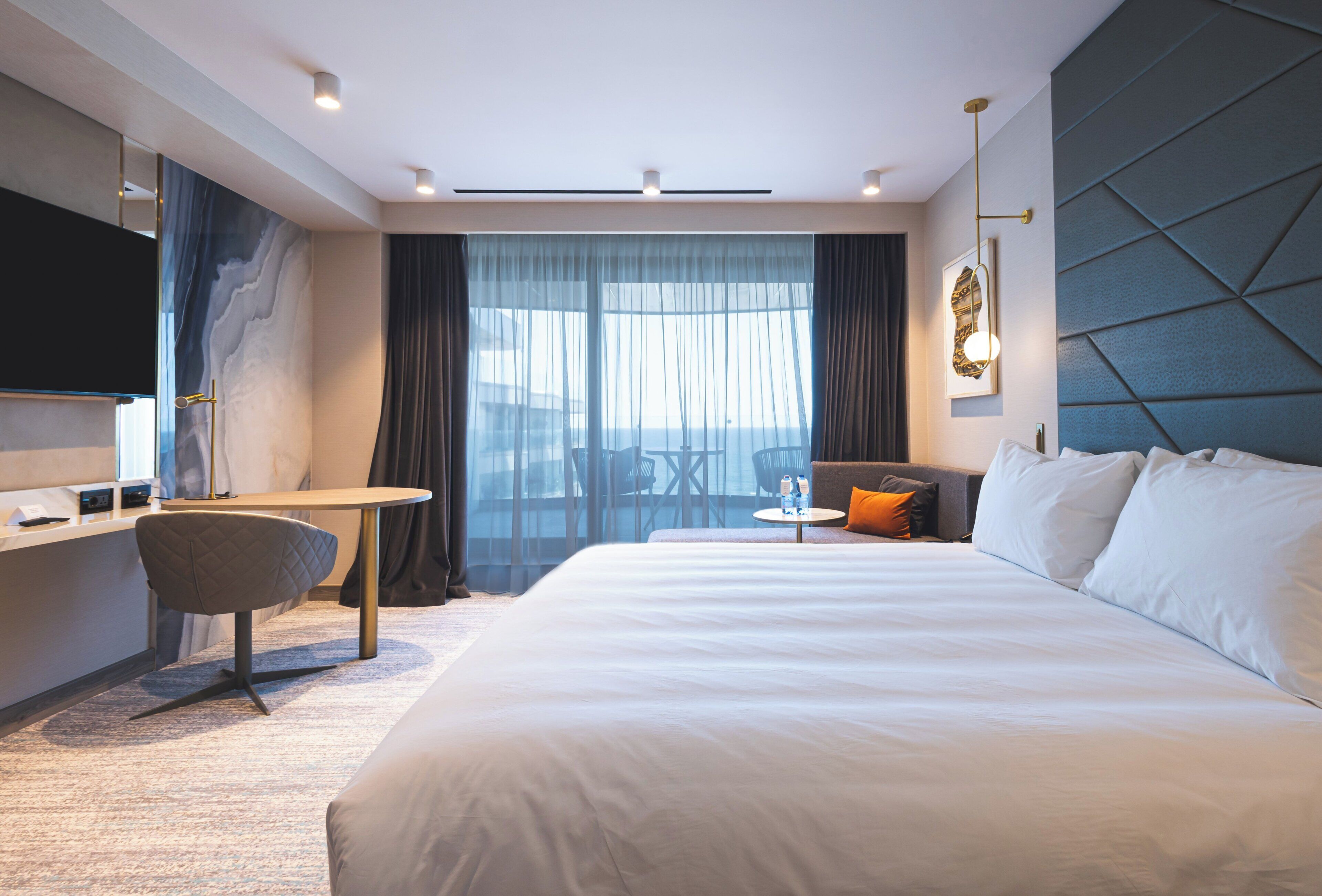 Een moderne hotelkamer met een groot bed, een bureau, een stoel en een televisie.