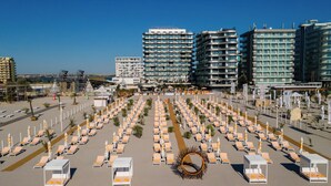 Een groot hotel met meerdere verdiepingen, een centrale binnenplaats met tal van ligbedden en parasols, en een helder uitzicht op de omgeving.