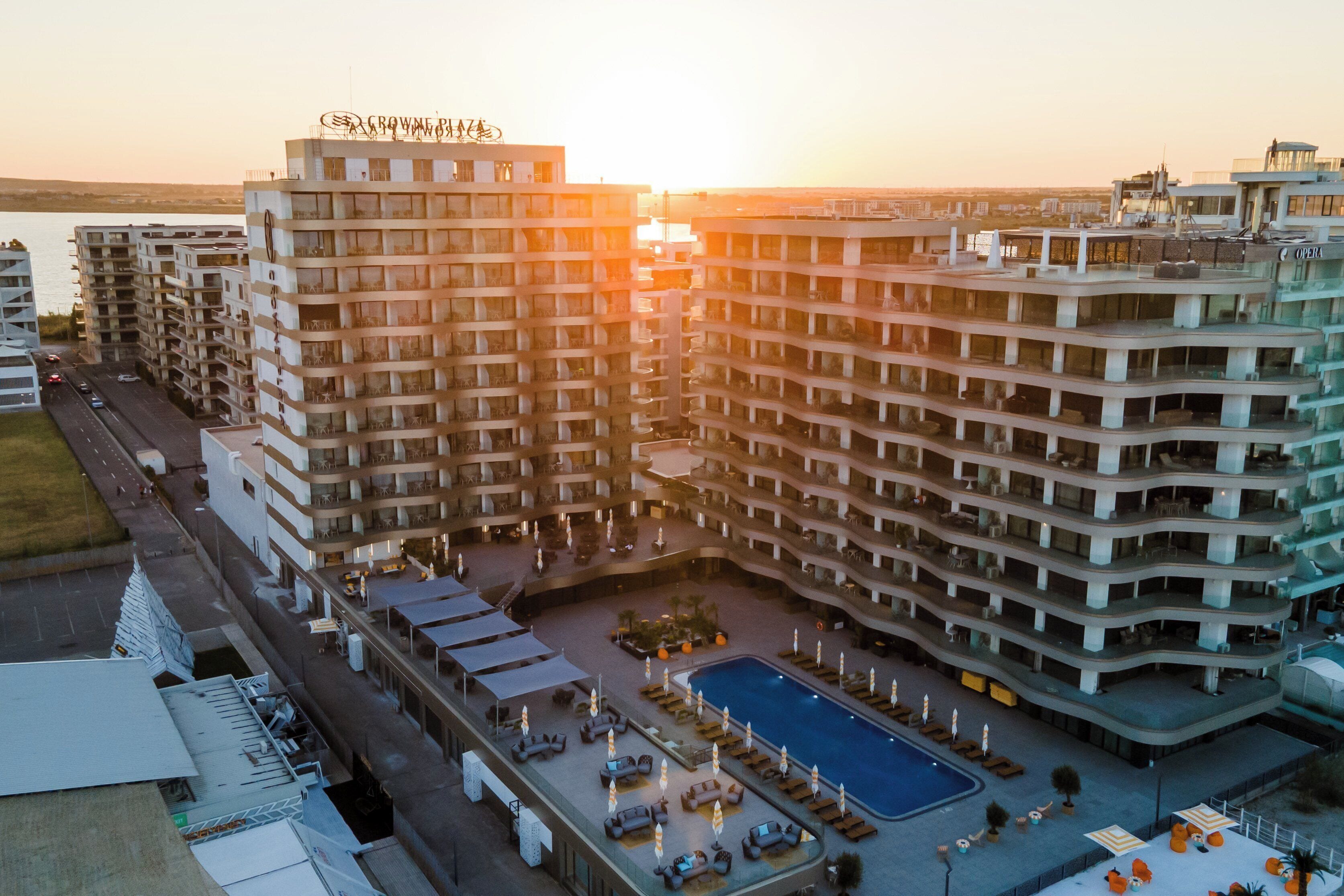 Un hôtel de grande hauteur doté de nombreux balcons, d’une piscine et offrant une vue sur le coucher de soleil.