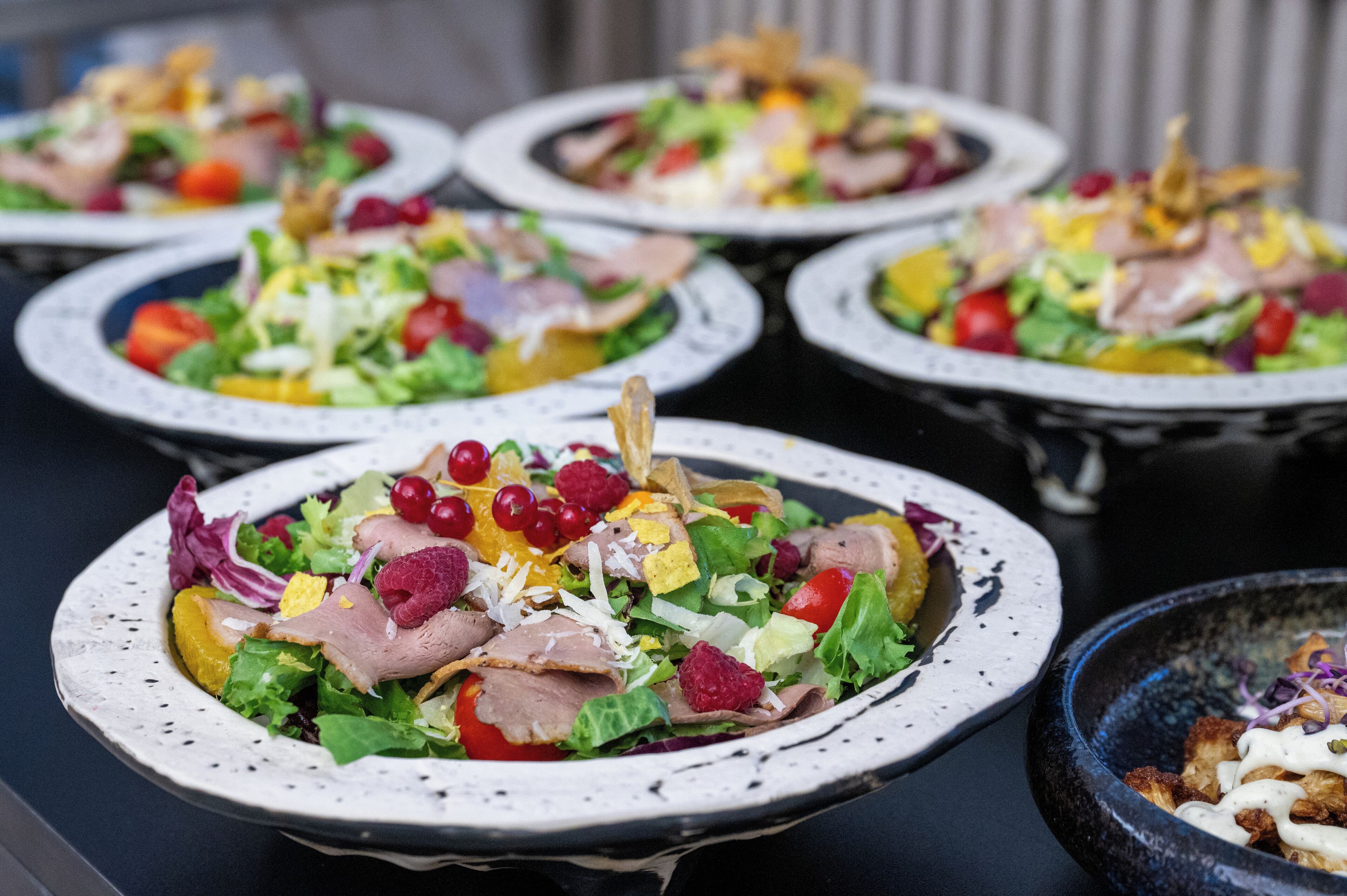 A buffet table with various dishes, including salads and meats, arranged on plates.