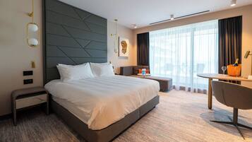 A modern hotel room with a large bed, a desk, and a chair.