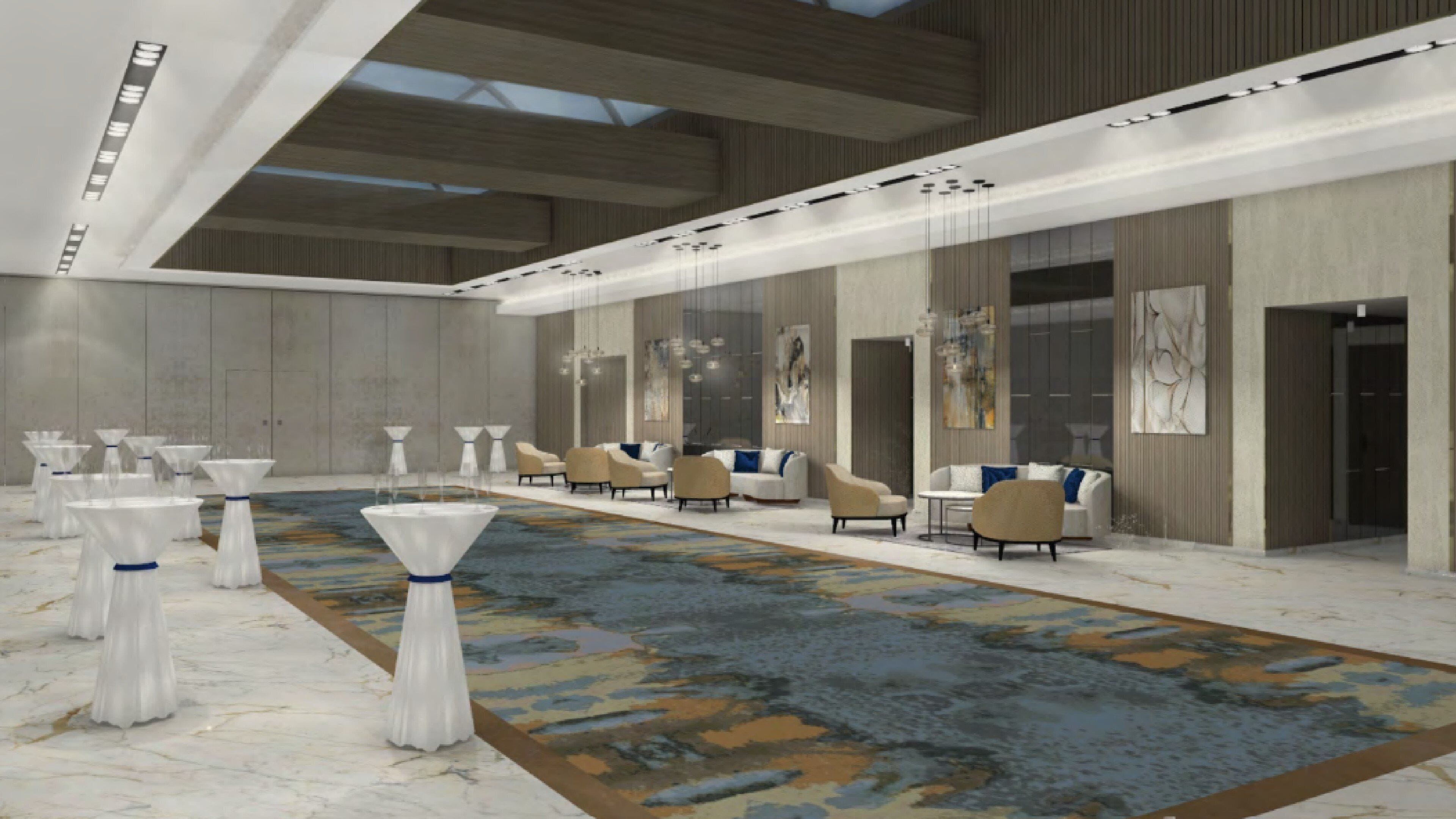 A spacious hotel lobby with a long reception desk, seating area with sofas and chairs, and a patterned carpet.