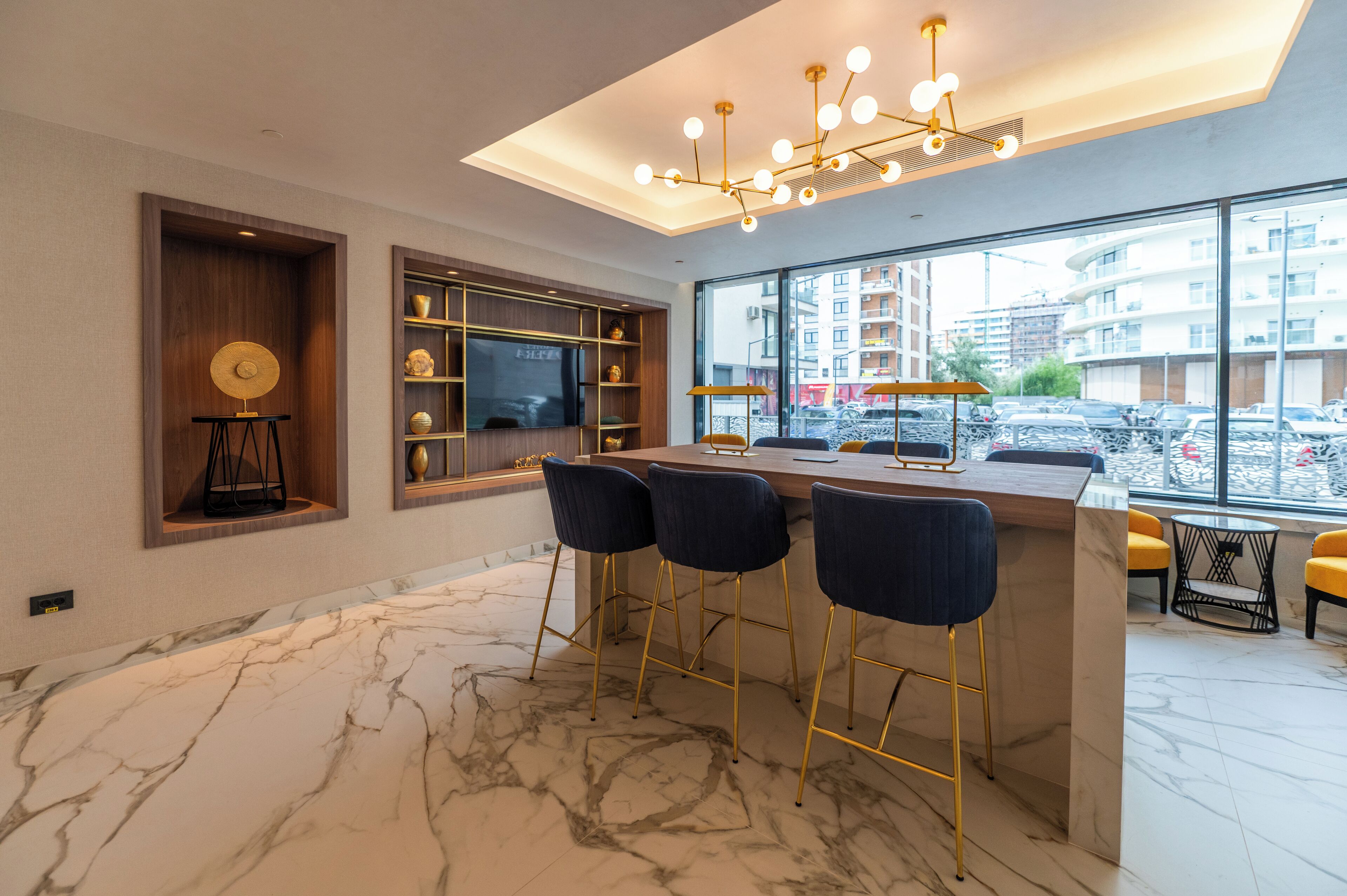 Cocina moderna con encimera de mármol, taburetes de bar y un amplio ventanal con vista a la ciudad.