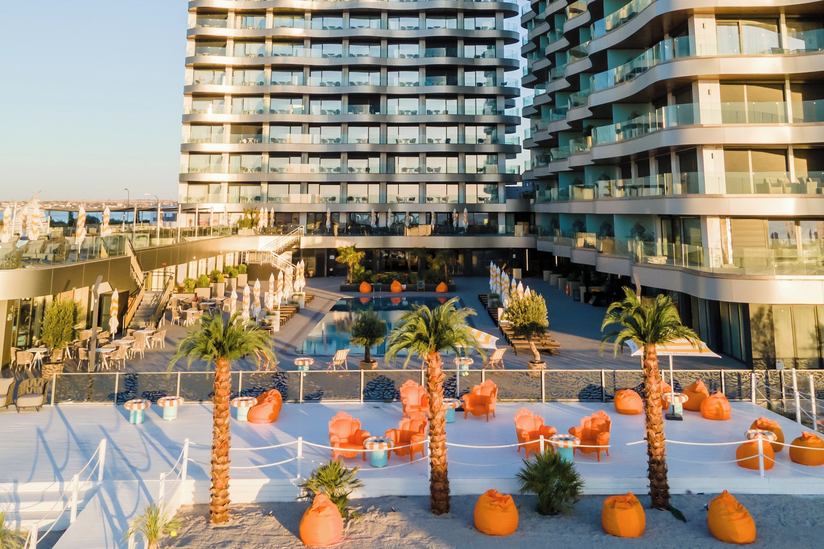A modern hotel with a rooftop pool area, multiple floors, and outdoor seating.