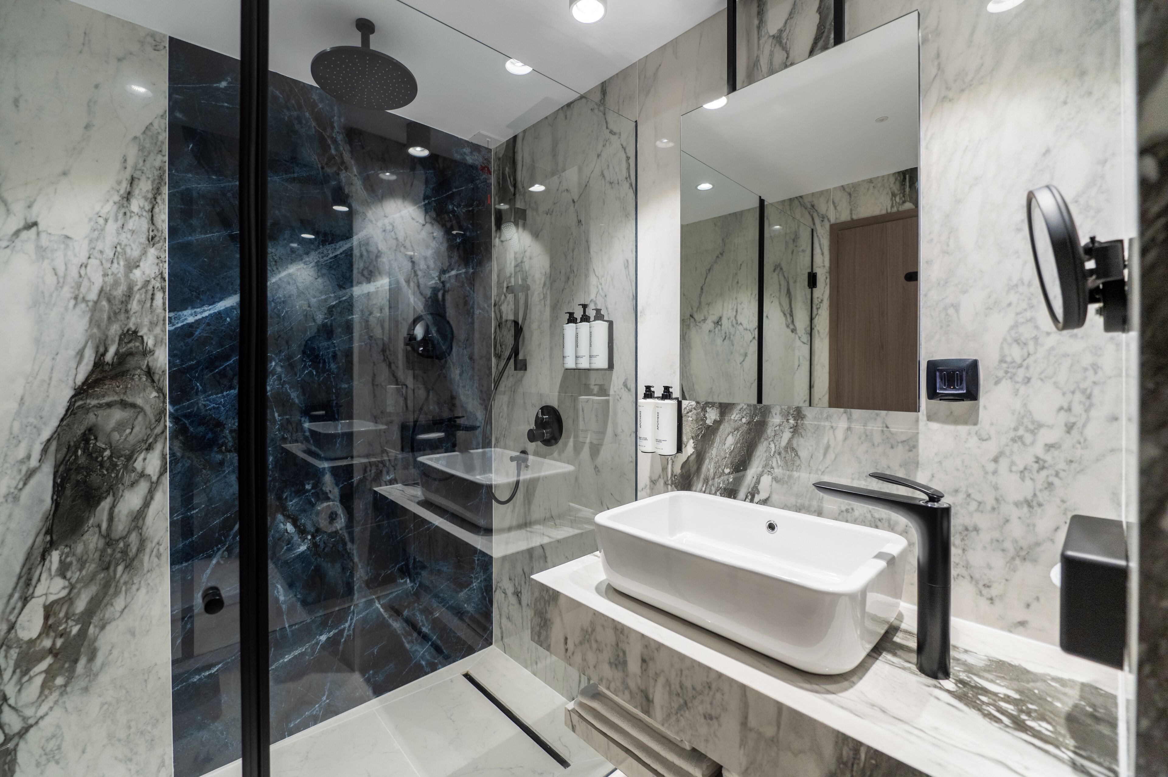 Un baño moderno con ducha envuelta en vidrio, una bañera independiente y un espejo grande.
