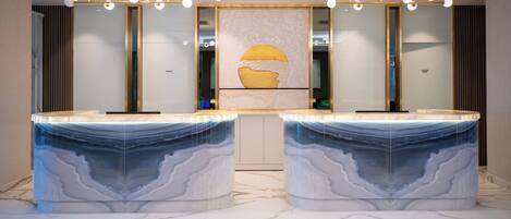 Une salle de bain moderne avec deux vasques en marbre, une œuvre d’art centrale et un luminaire au plafond.