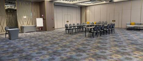 Un salón de conferencias con una larga mesa, sillas y una pizarra.