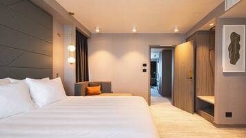 Une chambre d’hôtel moderne avec un grand lit, un bureau et un dressing.