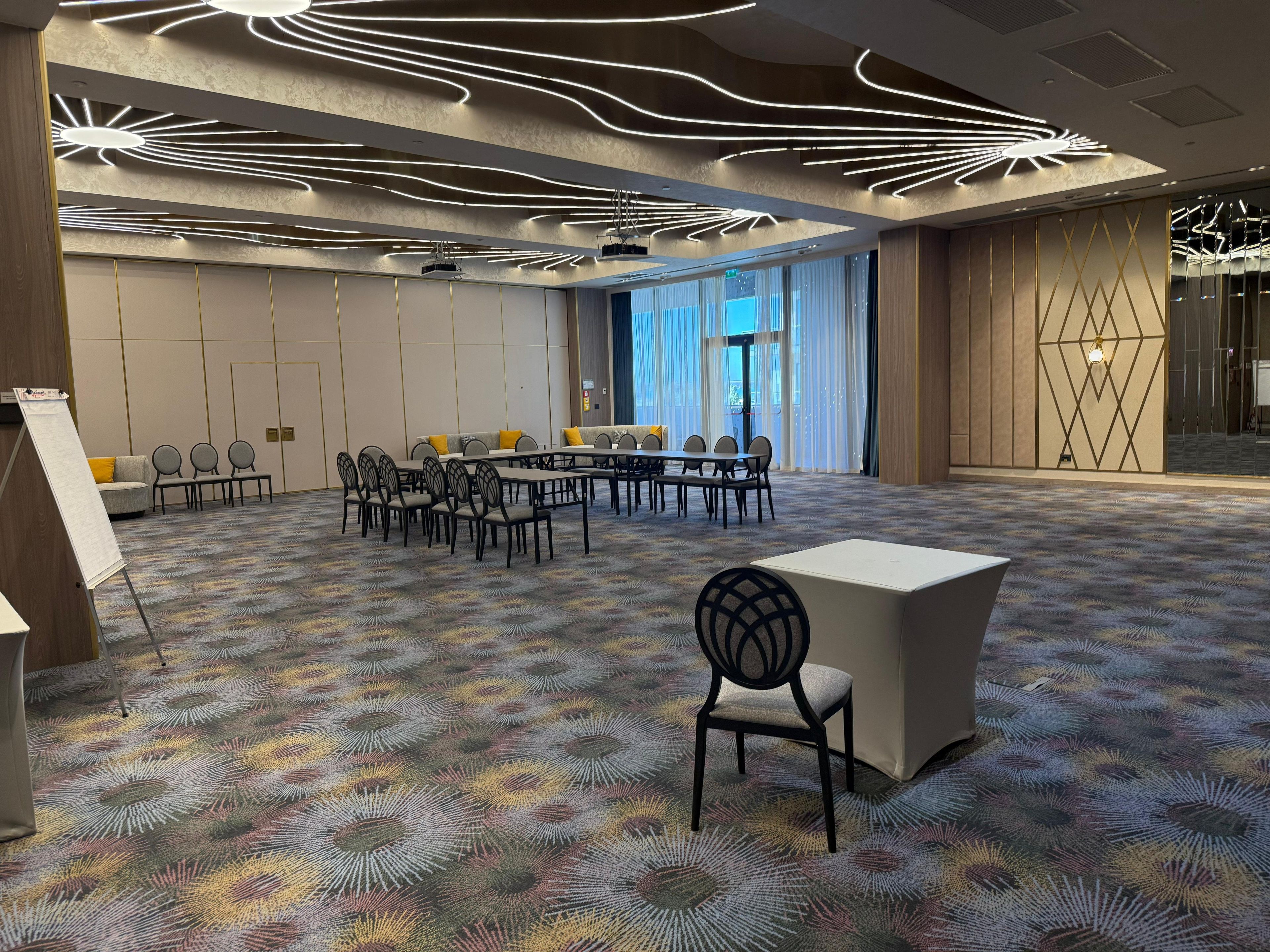 A conference room with a patterned carpet, a white table, and black chairs.