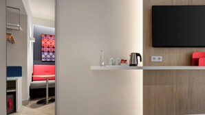 A modern hotel room with a bed, a small table with a kettle, cups, and a bottle. - Holiday Inn Express Porto Boavista by IHG (Porto)