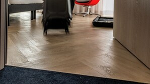 A hotel room with a bed, a red chair, a suitcase, and a wooden floor. - Holiday Inn Express Porto Boavista by IHG (Porto)