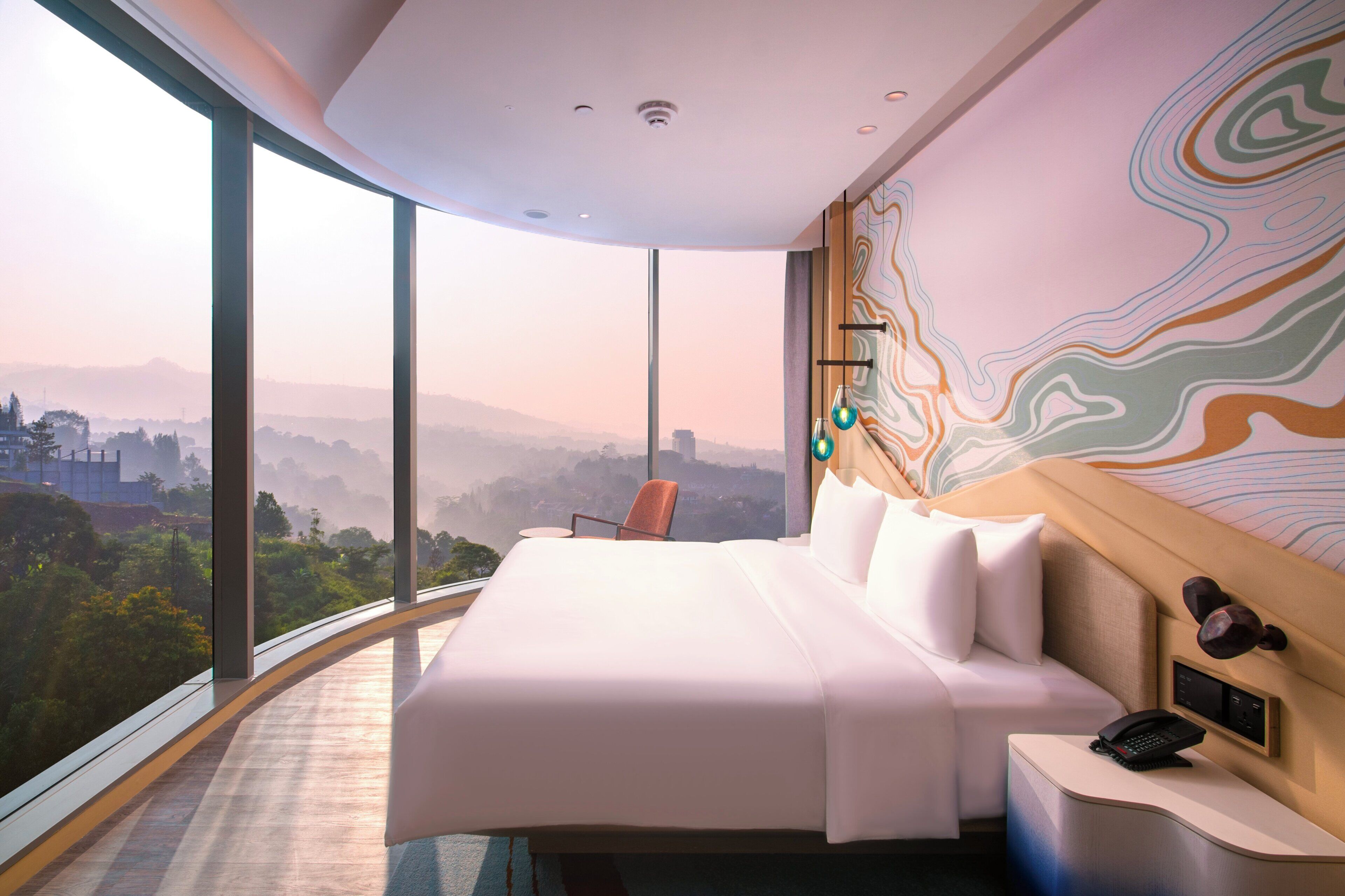 A modern hotel room with a large bed, a view of a cityscape, and a unique wall design.