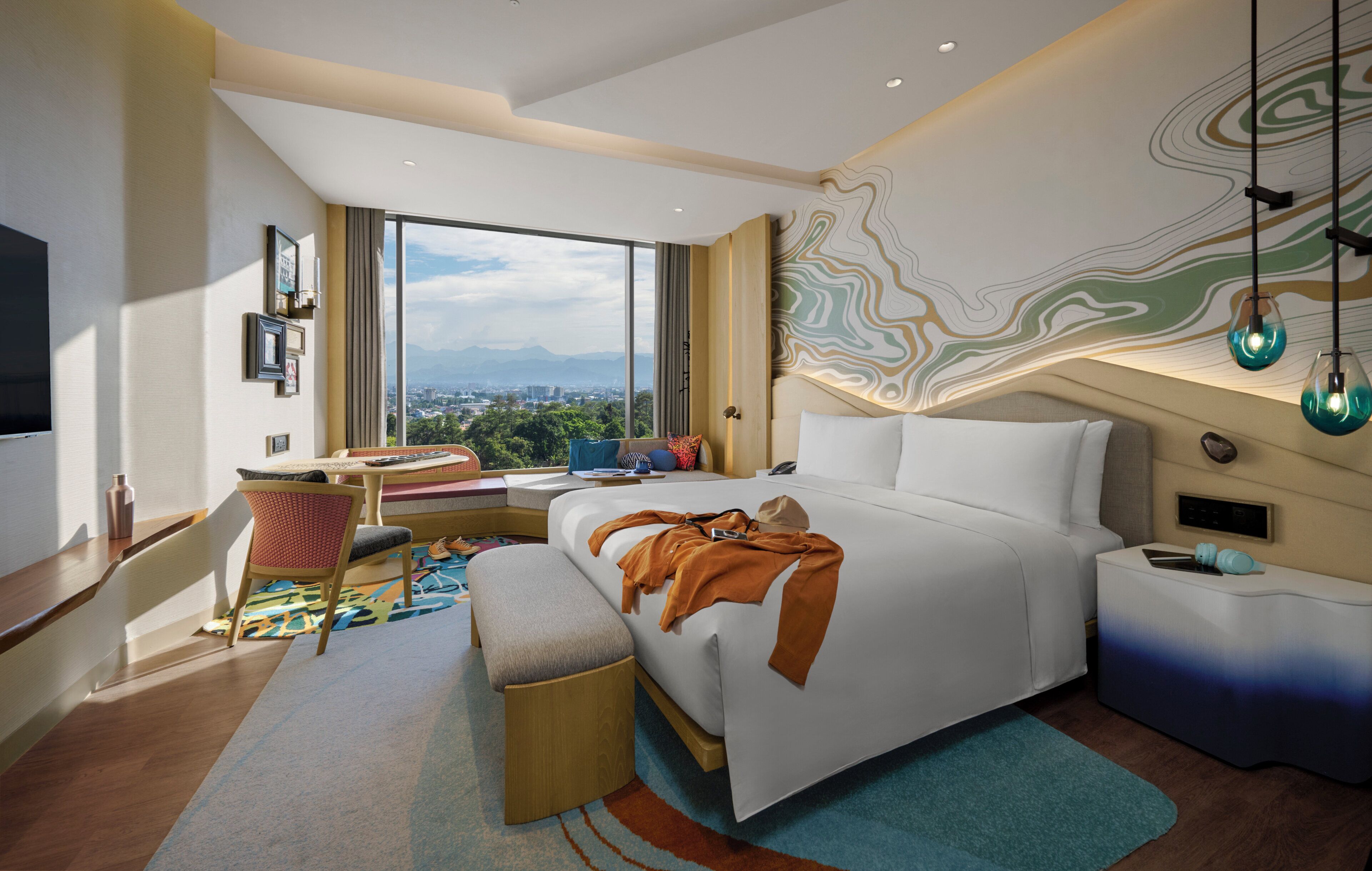 Una habitación de hotel moderna con una cama grande, un escritorio y vistas a la ciudad.