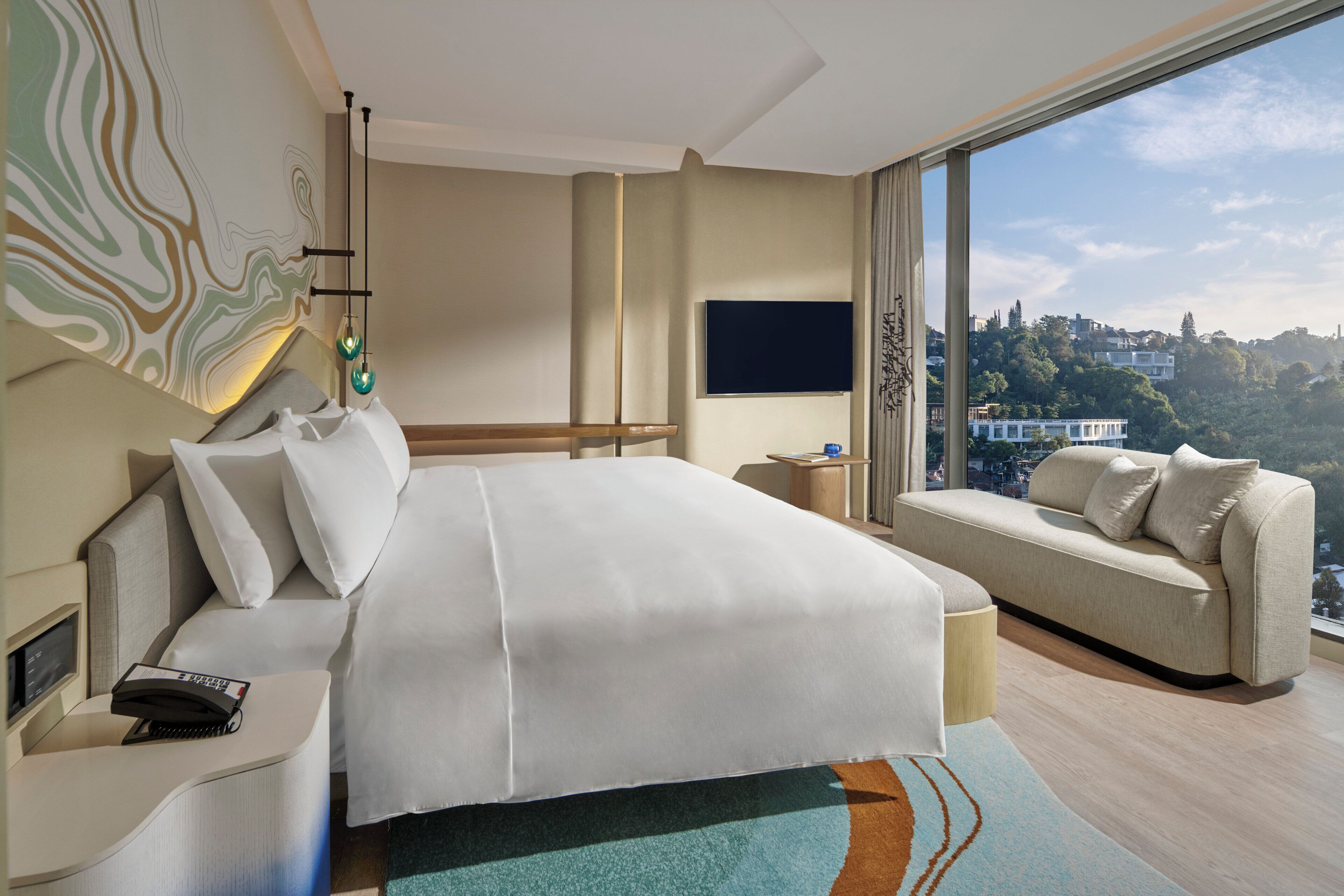 Ein modernes Hotelzimmer mit einem großen Bett, einer Couch, einem Fernseher und Blick auf die Stadt.