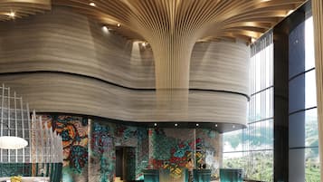 Un hall espacioso con techo curvo, pared de mosaicos y un amplio ventanal con vistas al exterior.