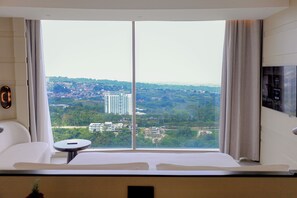 A hotel room with a large window, a bed, a small table, and a TV. - Hotel Indigo Bandung Dago Pakar by IHG (Bandung)