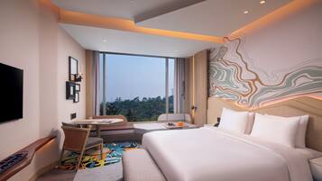 A modern hotel room with a large bed, a desk, and a view of the outdoors.
