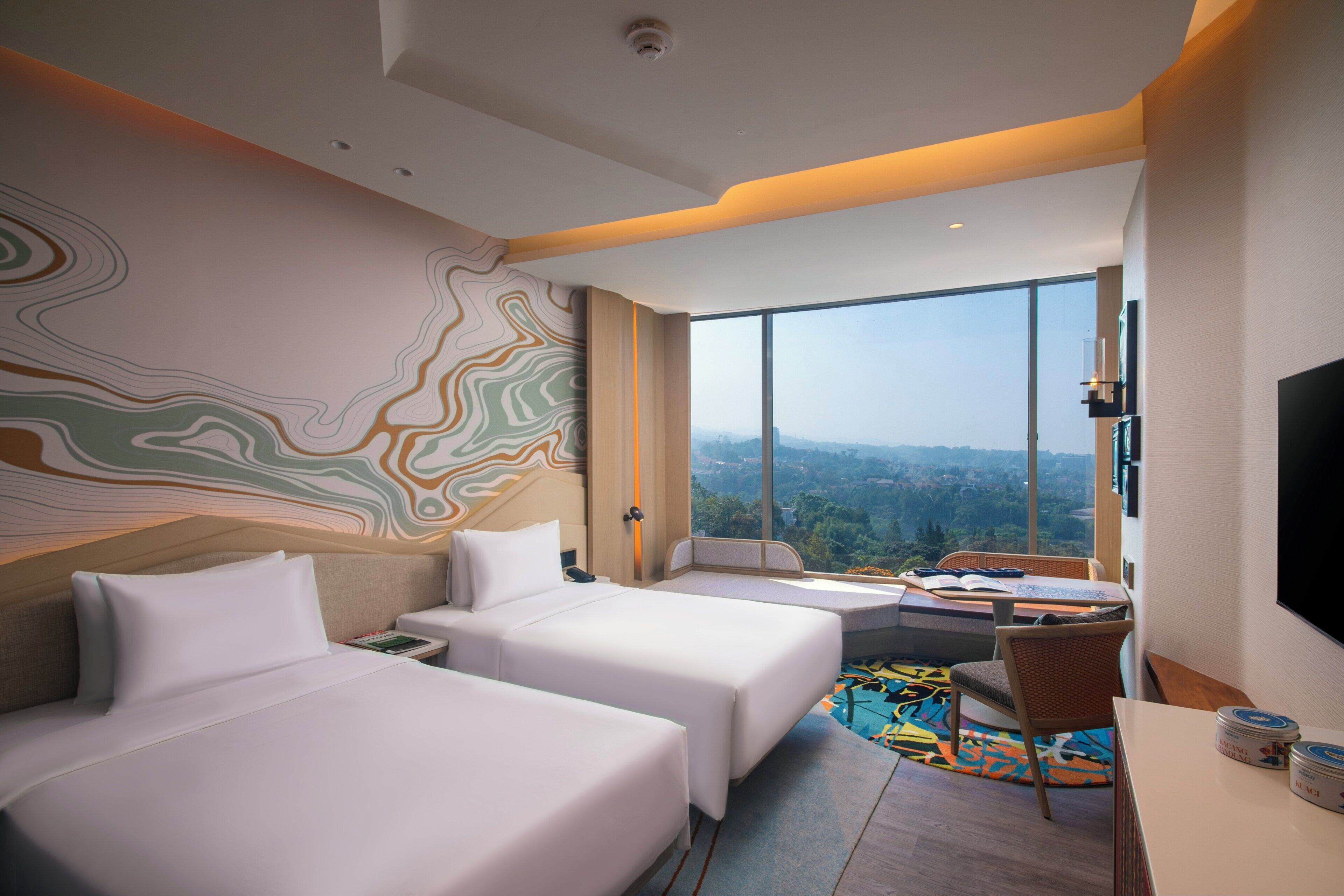 A hotel room with two beds, a desk, a chair, a TV, and a large window offering a city view.