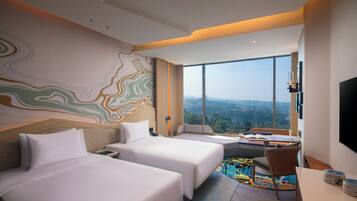 A hotel room with two beds, a desk, a chair, a TV, and a large window offering a city view.