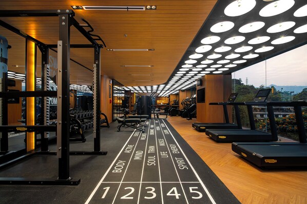 Un gimnasio con cintas de correr, máquinas de pesas y una pista de atletismo con mensajes motivacionales.