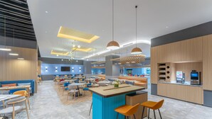 Un restaurant moderne doté d’un bar central, de plusieurs espaces pour s’asseoir et d’un éclairage contemporain.